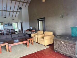 A spacious living area with a large sofa, two armchairs, and a wooden coffee table. A dining area with a table and chairs is visible in the background. - Lux Suites Leilani Annex Naivasha (Naivasha)