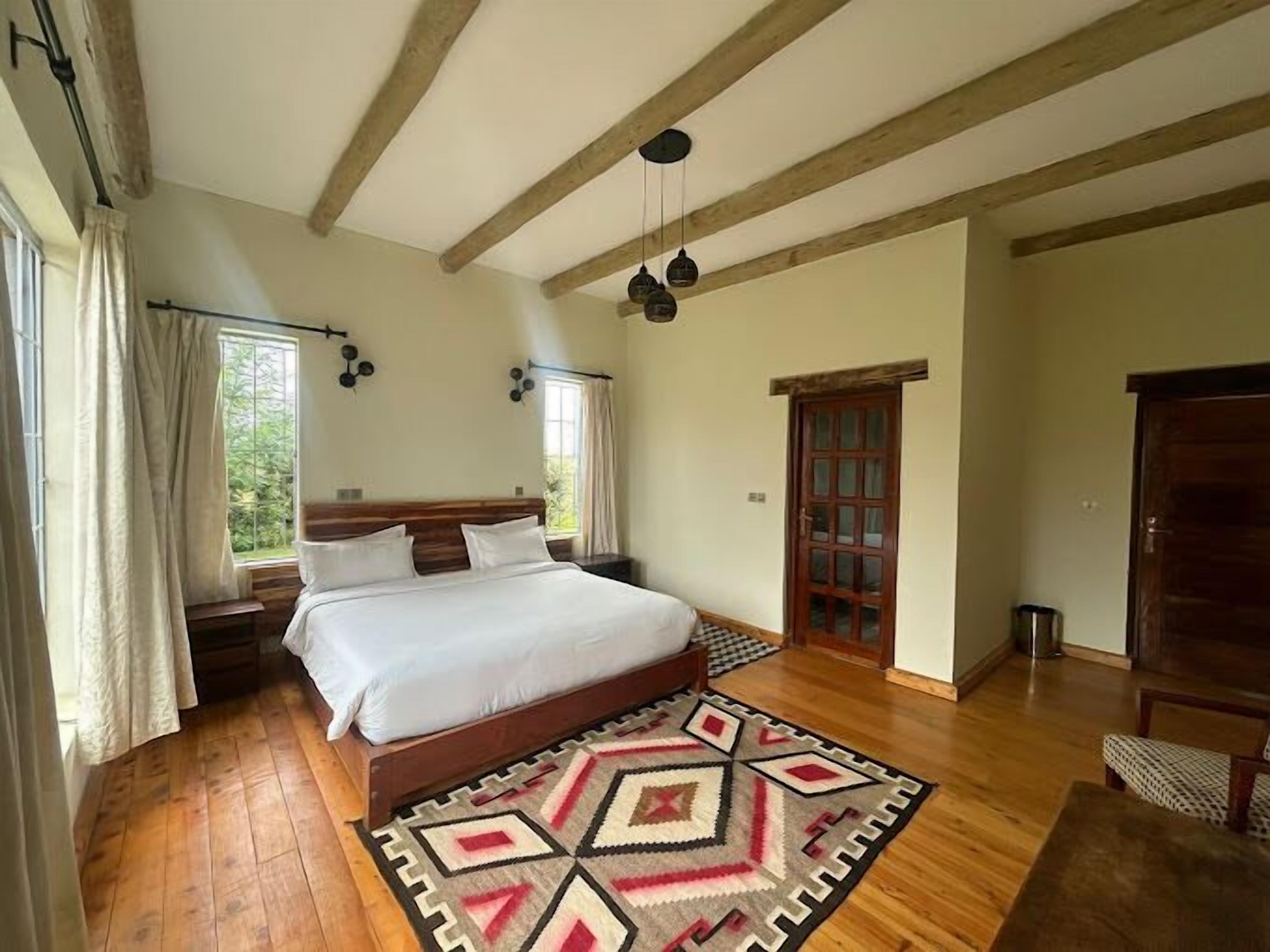 Een slaapkamer met een houten bed, een kamerkleed met dessin en een houten plafond.