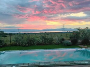 A swimming pool with a view of a sunset over a landscape with mountains and a body of water in the distance. - Lux Suites Leilani Annex Naivasha (Naivasha)
