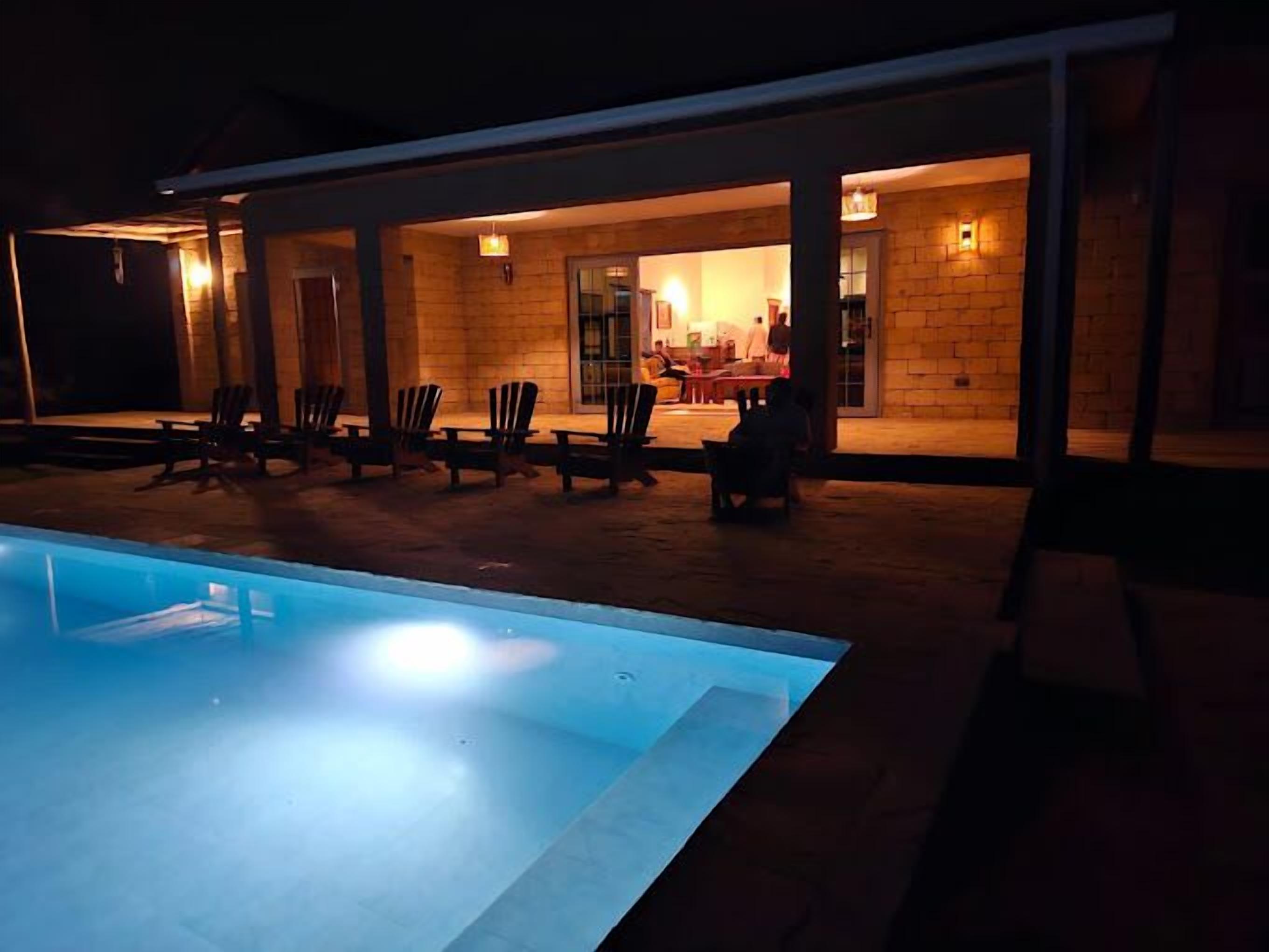 Un espace aménagé au bord de la piscine, avec des chaises longues et un coin repas comprenant des tables et des chaises.