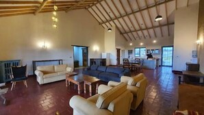 A spacious living area with a large sofa set, a dining table, and a kitchen in the background.