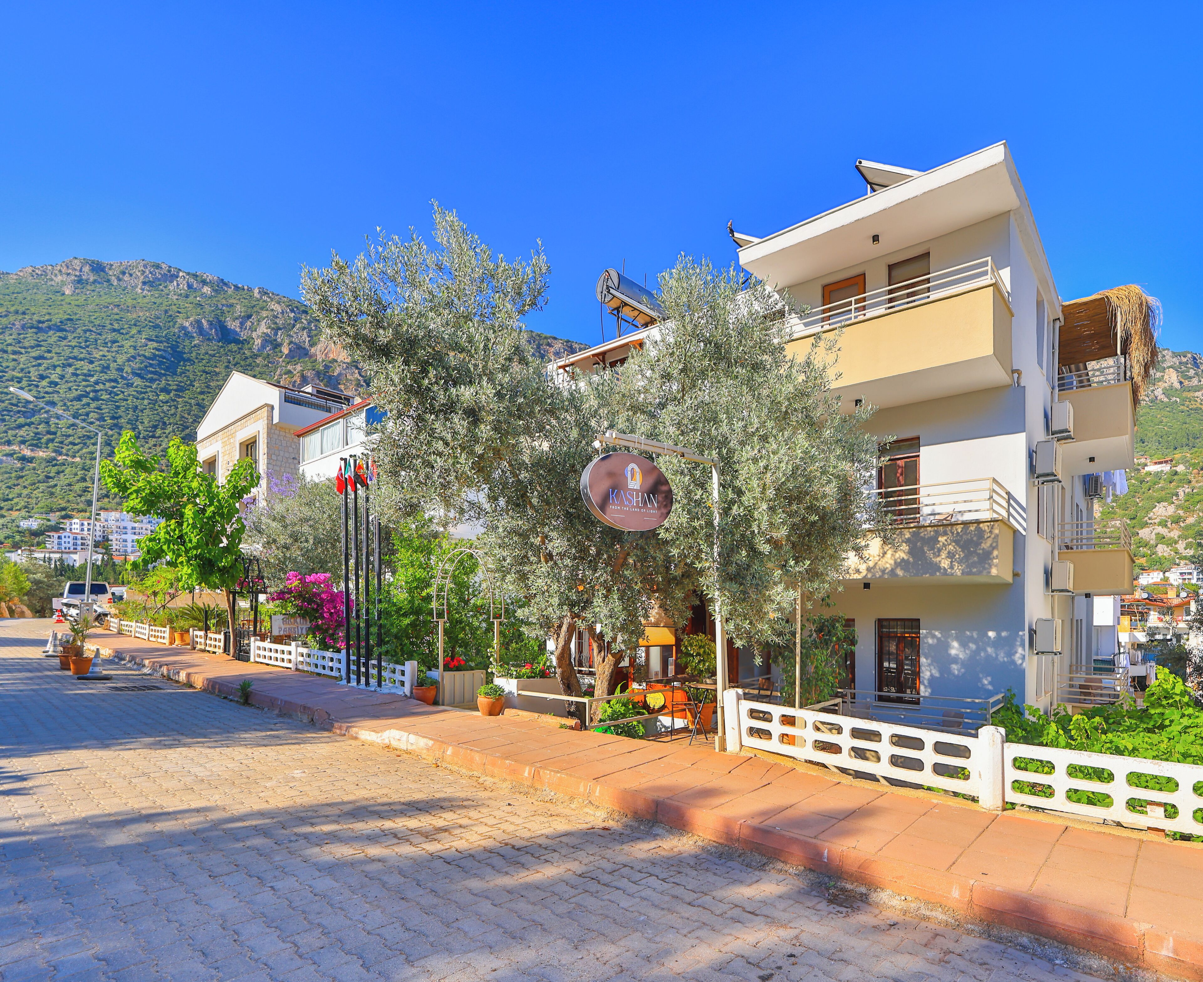 Un hotel con un letrero, una calle pavimentada y una montaña al fondo.