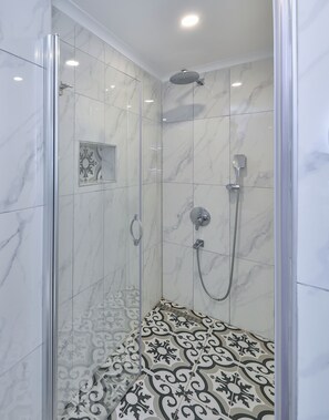 A modern shower with a glass door, a handheld showerhead, a wall-mounted showerhead, and a handheld faucet. - Kaşhan Hotel (Kas)