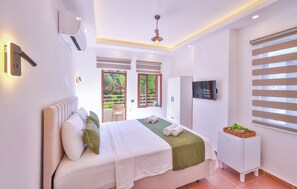 A bedroom with a bed, a TV, a wardrobe, and a balcony. - Kaşhan Hotel (Kas)