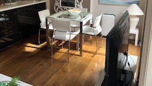A modern kitchen with white cabinets, a large mirror, and a dining area with a glass table and white chairs. - Chic 1-bedroom apartment with WiFi, AC in fabulous london Muslim douche 4 people (London)