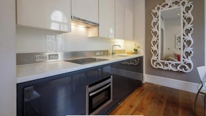 A modern kitchen with a sleek countertop, built-in oven, and a decorative mirror. - Chic 1-bedroom apartment with WiFi, AC in fabulous london Muslim douche 4 people (London)