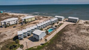 Un hotel frente al mar con varias construcciones, una piscina y vistas a la playa.