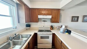 Una cocina con armarios de madera, una estufa blanca y un lavamanos doble.