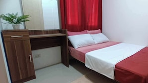Una habitación pequeña con cama, escritorio y una planta en maceta.