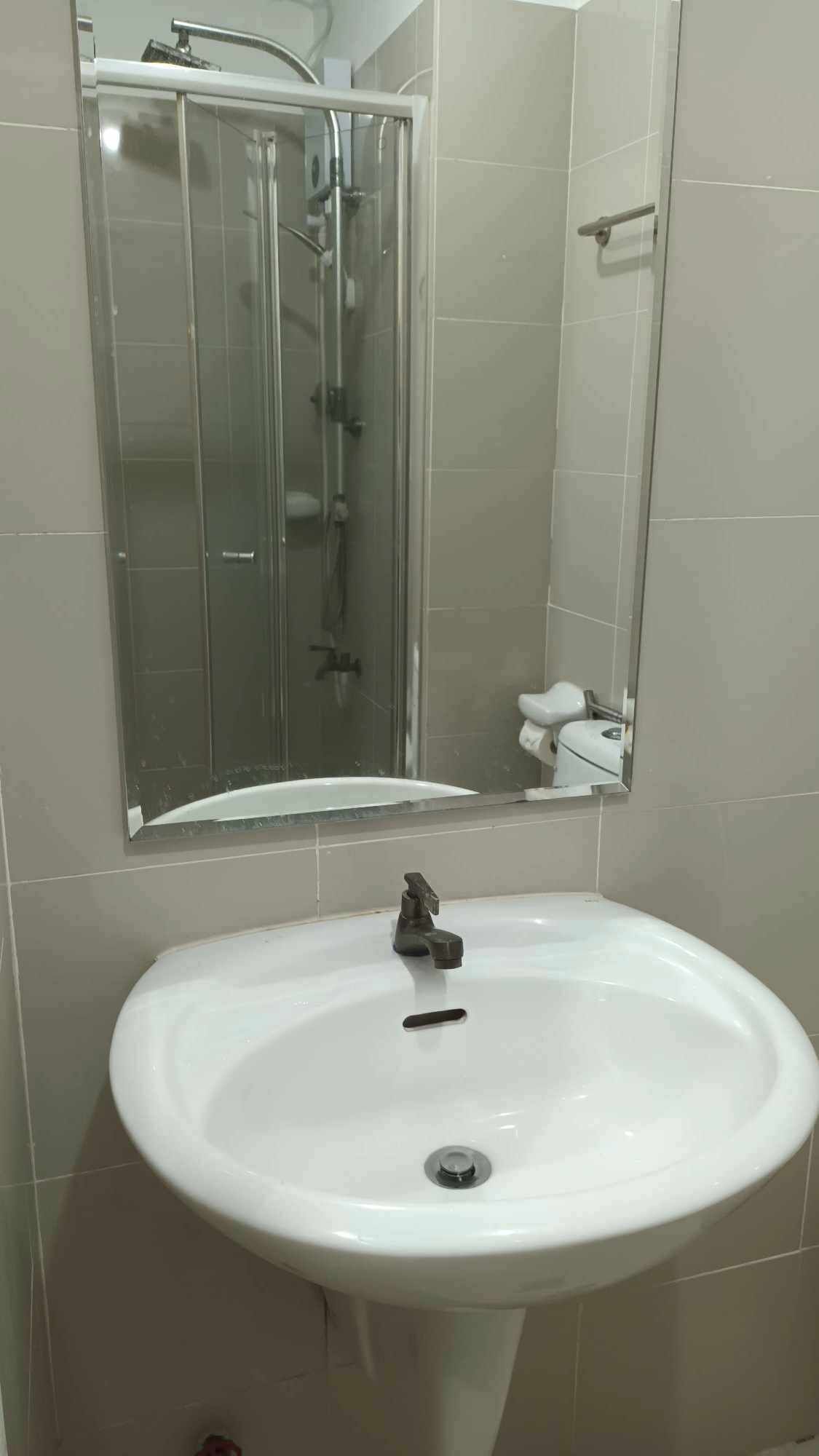 A bathroom with a glass shower enclosure, a white sink, and a mirror.