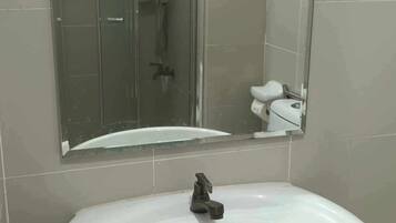 A bathroom with a glass shower enclosure, a white sink, and a mirror.