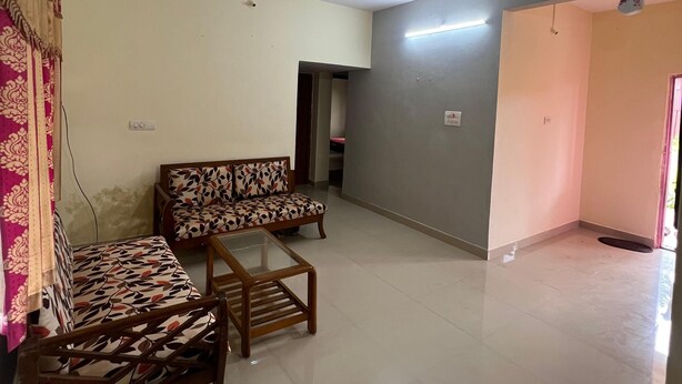 A living room with a sofa, a coffee table, and a ceiling fan. - Laxmi villa (Varanasi)
