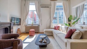 Ein Wohnzimmer mit Sofa, Sessel, Couchtisch und Heizkörper.