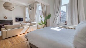Ein modernes Hotelzimmer mit einem großen Bett, einer Couch, einem Fernseher und Blick auf die Stadt.