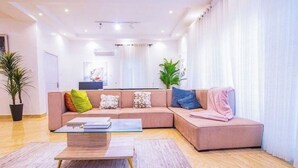 Un salon moderne avec un canapé d’angle, une table basse en verre et une plante en pot.