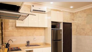 Une cuisine moderne équipée d’une cuisinière à gaz, d’un réfrigérateur en acier inoxydable et de meubles blancs.