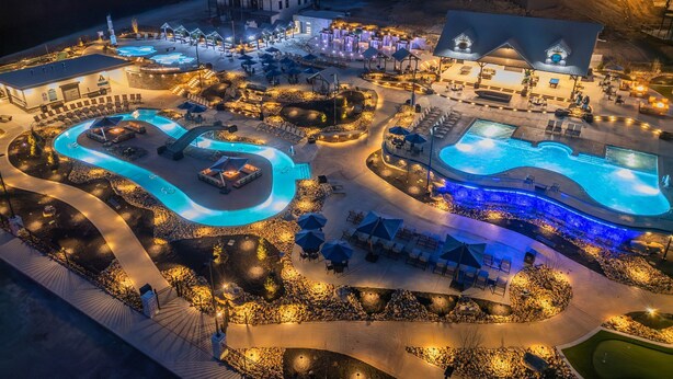 Een resort met meerdere zwembaden, buitenzitgedeeltes en verlichte paden.