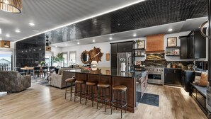 Een moderne keuken met een groot kookeiland, barstoelen en roestvrijstalen apparatuur.