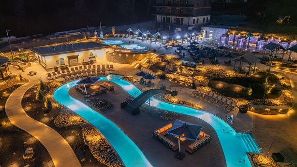 Ein Resort mit einem gewundenen Pool, Außenbereich zum Sitzen und einem mehrstöckigen Gebäude.