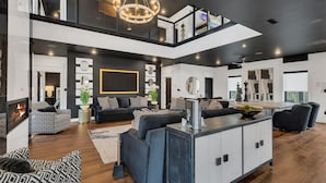Een moderne woonkamer met een open haard, een ruime bank, een eethoek en een keuken met een centraal kookeiland.