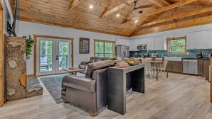 A spacious living area with a wooden ceiling, a dining table with chairs, and a kitchen in the background. - New!Min Away from Gatinburg,Pool Table, (Gatlinburg)