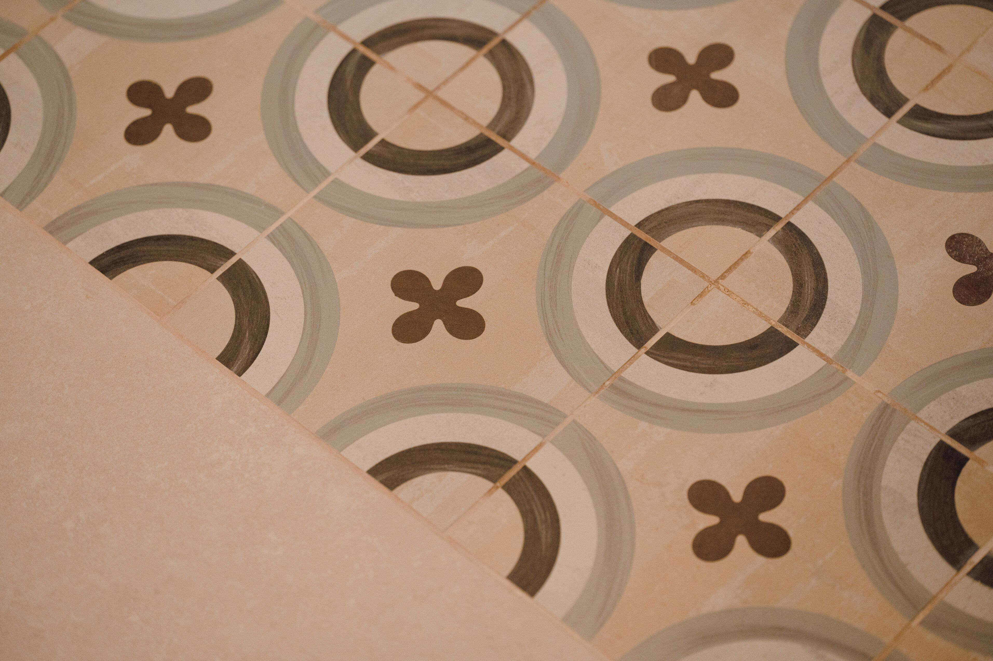 Primer plano de un suelo de baldosas con diseños geométricos circulares y en forma de cruz.