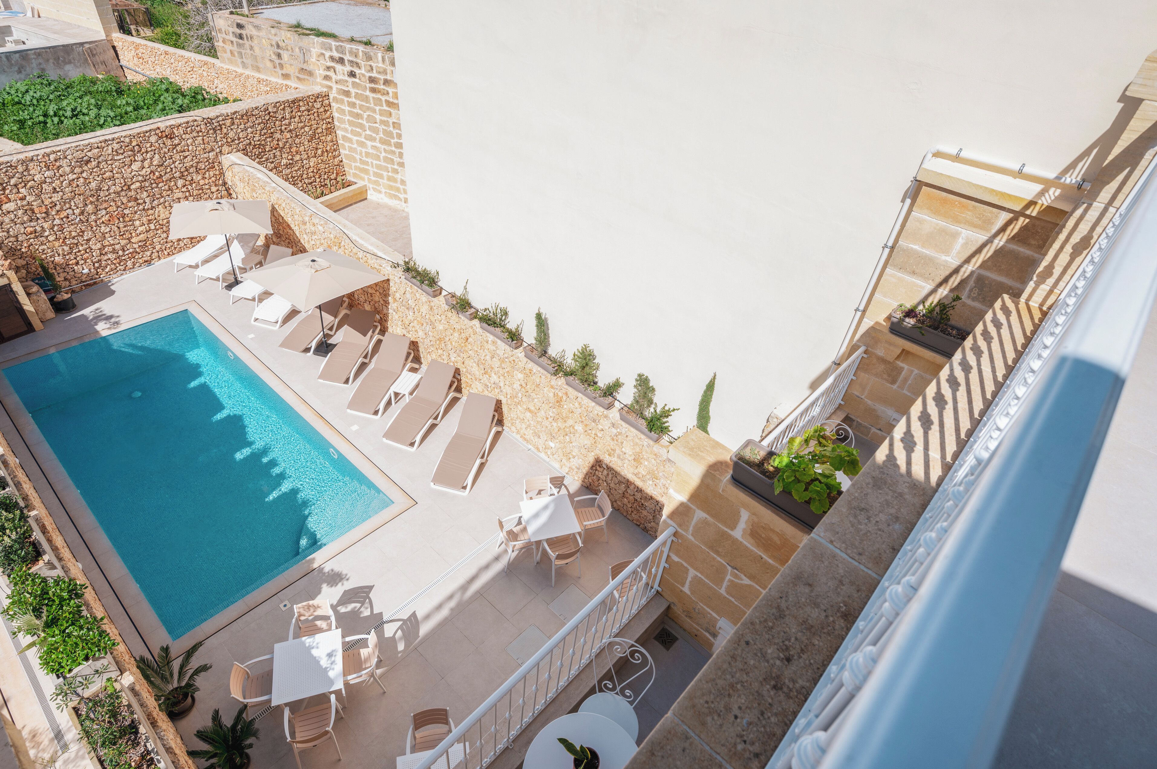 Un área de piscina en la azotea con sillones de descanso y una piscina.