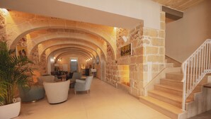 A spacious lobby with a stone archway, a staircase, and modern seating. - Silla Boutique B&B (Xagħra)