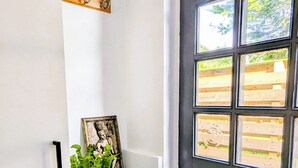 Eine weiße Wand mit einem Regal, auf dem ein gerahmtes Bild und ein Blumentopf stehen.
