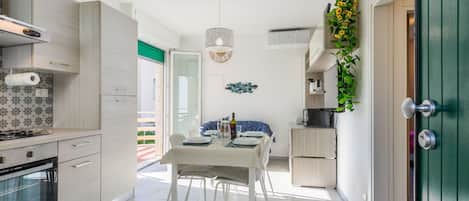 A modern kitchen with a dining area, a built-in oven, and a dining table set for four.