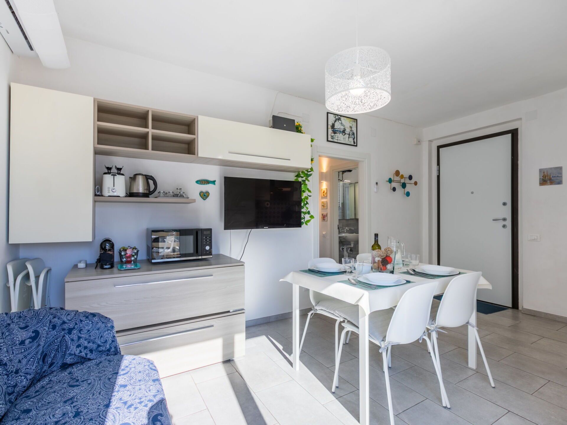 Una cuina moderna amb armaris blancs, un microones i una zona de menjador amb taula preparada per a dues persones.