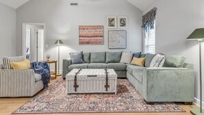 A living room with a sectional sofa, a striped armchair, and a patterned rug.
