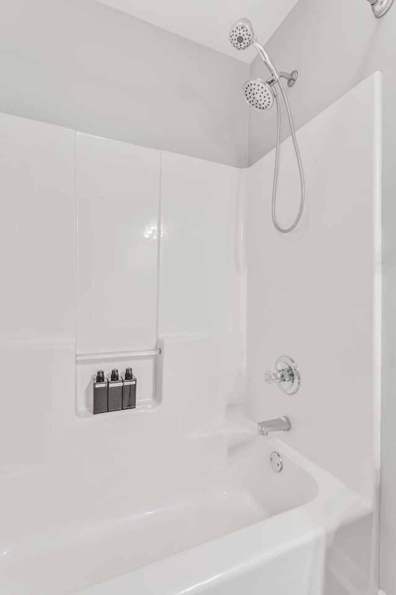 A modern bathroom with a freestanding bathtub, a handheld showerhead, and a wall-mounted faucet.