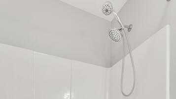 A modern bathroom with a freestanding bathtub, a handheld showerhead, and a wall-mounted faucet.