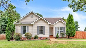 A two-story house with a front porch, a small front yard, and a wooden fence.