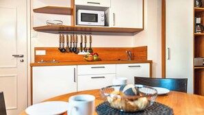 A compact kitchen with white cabinets, a microwave, and a hanging utensil rack.