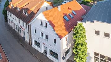 A multi-story building with a red-tiled roof, white walls, and multiple windows.