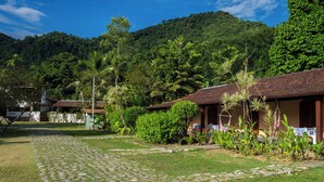 A courtyard with cobblestone paths, surrounded by lush greenery and a hillside. - Pousada Tarituba (Paraty)