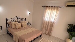 A bedroom with a bed, a rug, a potted plant, and a curtain. - Villa mayline (Arkou)