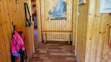 Un couloir en bois avec un banc, une affiche et un tapis bleu à l’entrée.