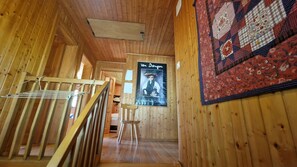 A wooden interior with a staircase, a poster of Van Gogh, and a quilt on the wall.