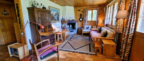 A cozy living room with a fireplace, wooden furniture, and a rug.