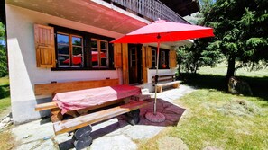 Una cabaña de madera con un banco y un paraguas rojo en el exterior.