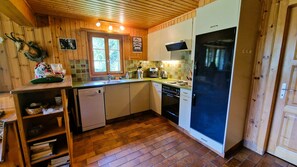 Una cocina compacta con armarios de madera, lavavajillas, estufa y refrigerador.