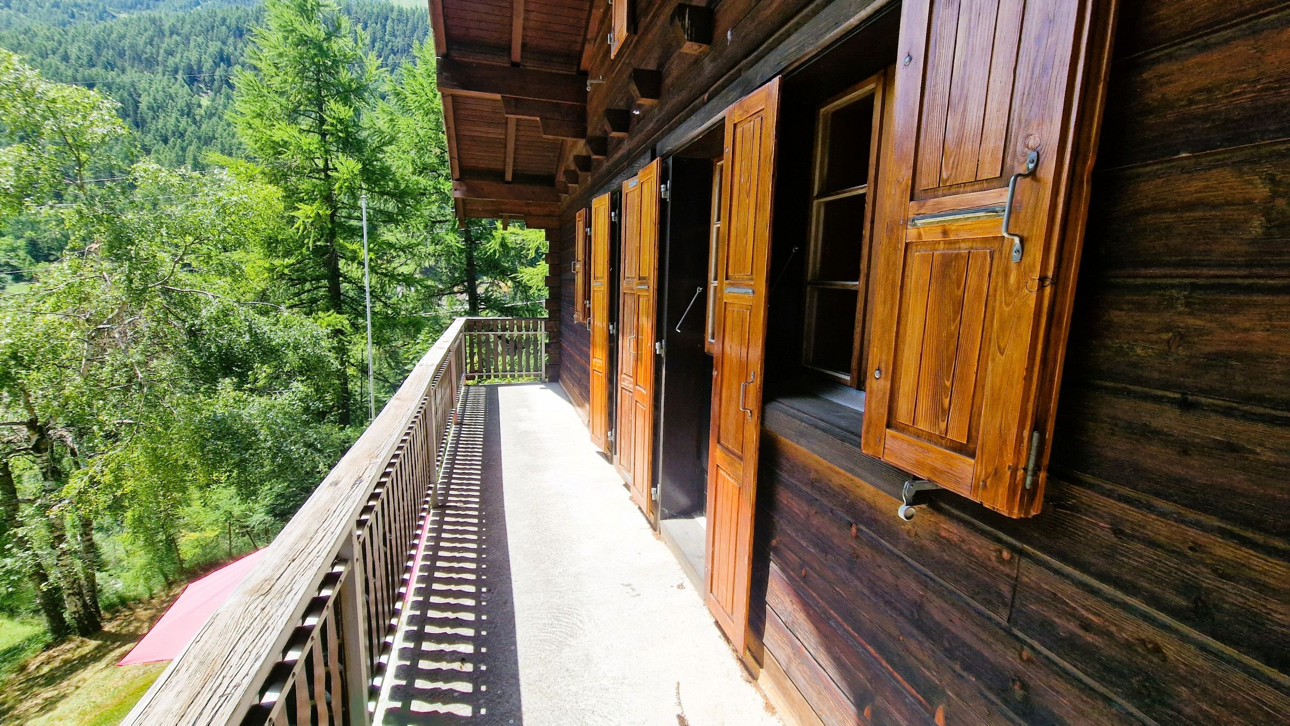 Un bâtiment en bois doté d’un balcon donnant sur une vallée boisée.