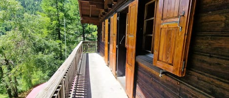 A wooden building with a balcony overlooking a forested valley.