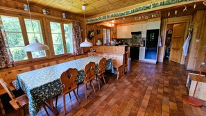 Una cabaña de madera con comedor, cocina y un ventanal grande.