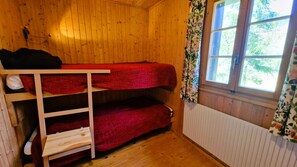 Una habitación pequeña de madera con literas y una ventana.