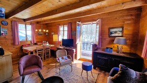 A cozy cabin interior with a dining area, a television, and a fireplace. - Chalet Dar El Jebel - 6 personnes (Evolène)