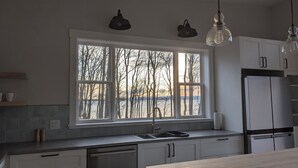 Eine moderne Küche mit großem Fenster, Edelstahlgeräten und Pendelleuchten.
